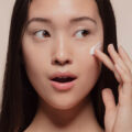Close-up of woman applying skin cream to her cheek